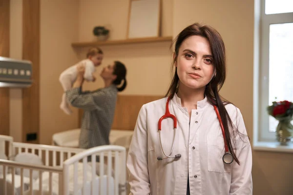 Serene Pediatrische Arts Bezoekt Jonge Vrouwelijke Ouder Met Zuigeling Ziekenhuis — Stockfoto