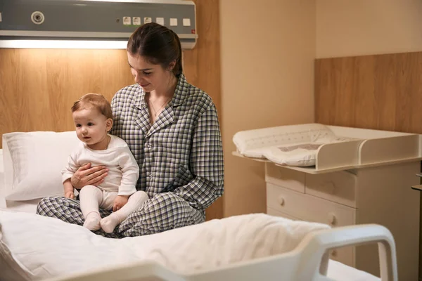 Glimlachende Jonge Vrouw Pyjama Zitten Met Haar Kalme Kind Ziekenhuisbed — Stockfoto
