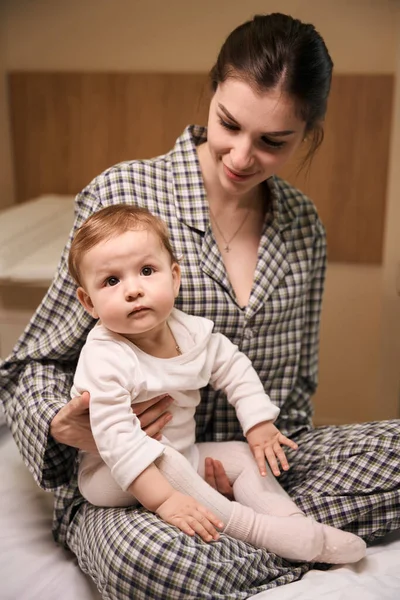 Sonriente Joven Hembra Pijama Sentada Con Triste Bebé Hospitalizado Cama —  Fotos de Stock