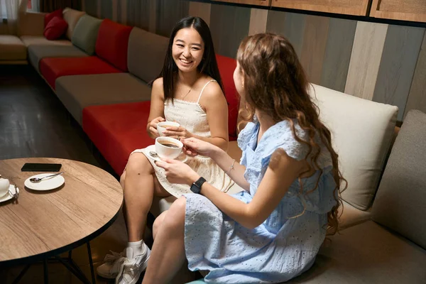 Yandan Bakınca Gülümseyen Kadınların Otelin Lobisinde Kahve Içerken Çekilmiş Fotoğrafı — Stok fotoğraf