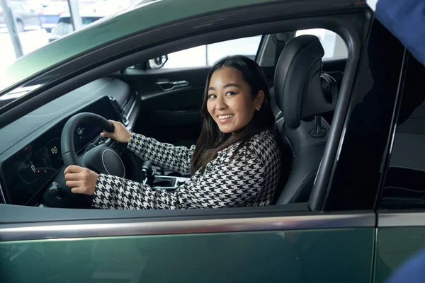 Young female customer is testing a new car, a woman driving a modern car