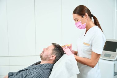 Genç kozmetik uzmanı kafa derisinde bir plazma kaldırma işlemi gerçekleştirir.