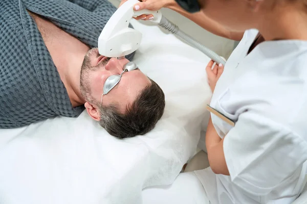 Kosmetolog Wykonuje Zabieg Fotorejuvenation Mężczyzny Średnim Wieku Lekarza Pacjenta Goglach — Zdjęcie stockowe