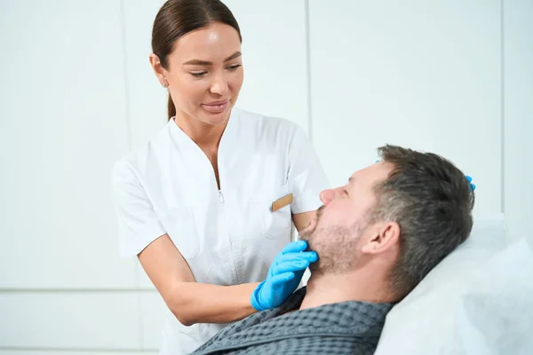Cosmetologista Profissional Examina Rosto Paciente Meia Idade Homem Confortavelmente Assentado — Fotografia de Stock