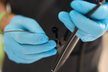 Doktorun elleri nitrile eldivenlerle endoskop kanalına ince bir tüp yerleştirirken yakın plan.