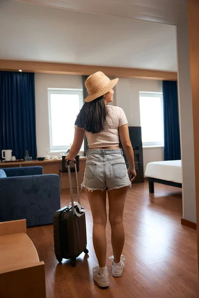 Touristin Mit Kopfbedeckung Und Koffer Auf Rädern Steht Hostel Zimmer — Stockfoto