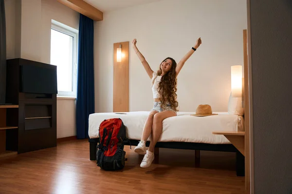 Yatakta Sırt Çantasının Yanında Oturan Otel Odasında Kaldıran Genç Bir — Stok fotoğraf