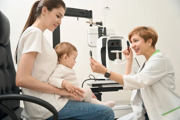 Glada Kvinnliga Ögonläkare Undersöker Små Patientögon Med Ockluder Och Förstoringsglas — Stockfoto