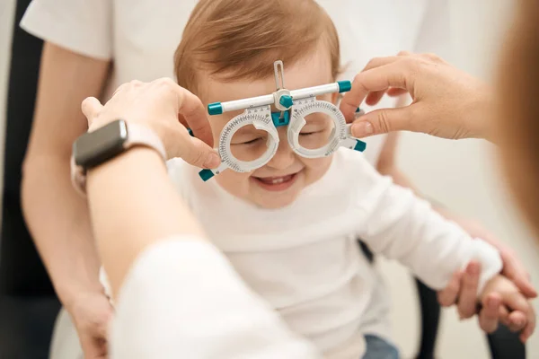 女性眼科手上の眼科試験フレーム上の楽しいです幼児で親存在 — ストック写真