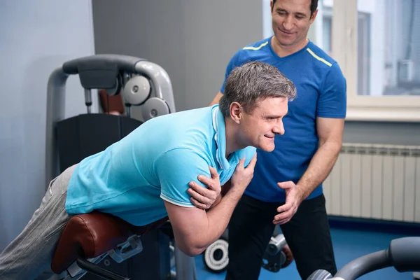 Tevreden Mannelijke Presteren Back Extension Fitnessapparatuur Onder Begeleiding Van Personal — Stockfoto