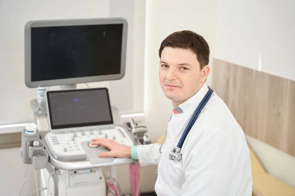 Cardiologo Maschile Che Lavora Dietro Attrezzature Clinica Guardando Fotocamera — Foto Stock