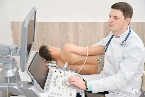 Mladý Lékař Bílém Plášti Provádějící Ultrazvukovou Diagnostiku Nahlížející Monitoru Vybavení — Stock fotografie