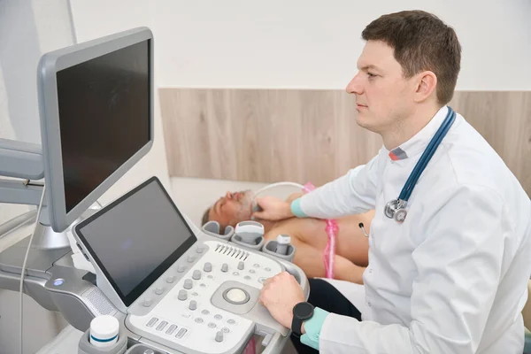 Médico Avental Branco Com Estetoscópio Sentado Perto Paciente Fazendo Diagnóstico — Fotografia de Stock