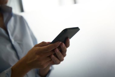 Yetişkin bir kadının cep telefonuna mesaj yazarken çekilmiş fotoğrafı.