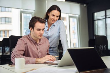 Utangaç ofis çalışanı dizüstü bilgisayardaki çalışmalarını memnun bayan patrona gösteriyor.