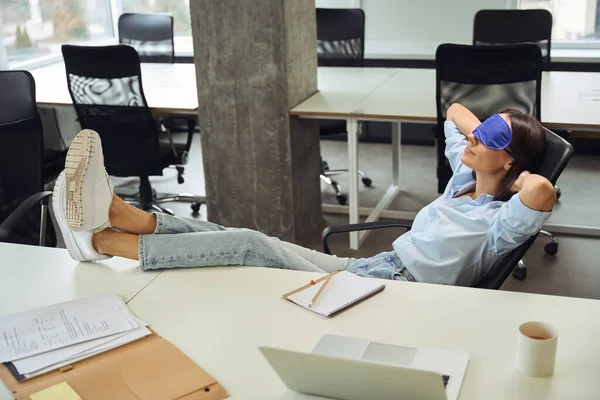 坐在开放式办公室里 脚踏在桌子上 戴着睡眠面罩的公司员工安静下来 — 图库照片