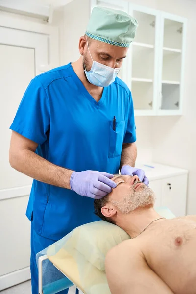 Maskeli Doktor Erkek Bir Müşterinin Göz Kapaklarına Yama Yapıştırıyor Estetik — Stok fotoğraf