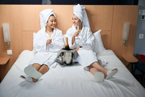Kafalarında Havlu Beyaz Önlüklerle Çok Kültürlü Genç Bayanlar Oteldeki Yatakta — Stok fotoğraf