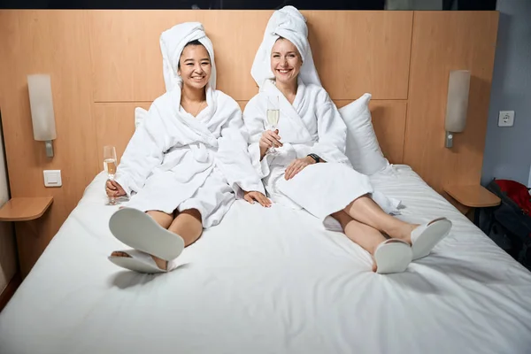 Flickvänner Sängen Dricker Champagne Hotellrummet Två Kvinnor Badrockar Sängen Dricker — Stockfoto