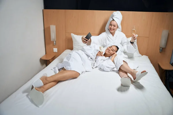Tyttöystävät Ottavat Selfien Hotellihuoneessa Kaksi Naista Lepää Sängyllä Hotellihuoneessa — kuvapankkivalokuva