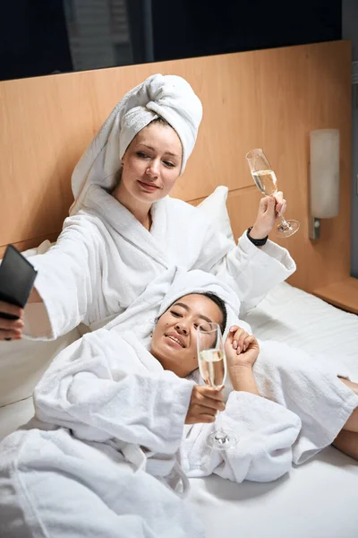 两个女人躺在床上在旅馆房间里自投罗网 女伴们在旅馆房间的床上休息 — 图库照片