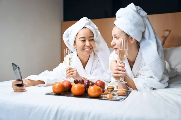 Selfie Two Girlfriends Glasses Fruit Hotel Drinking Champagne Bathrobes Bed — Stock Photo, Image