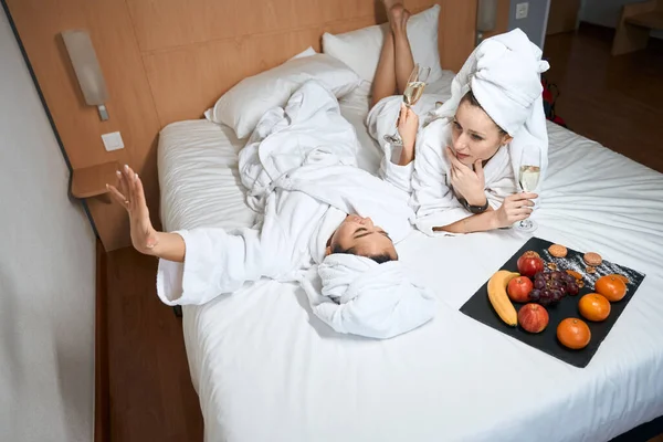 Bardaklı Meyveli Bornozlu Kız Arkadaşların Oteldeki Yatakta Konuştuğu Iyi Manzara — Stok fotoğraf