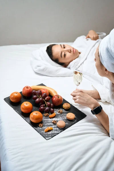 シャンパンと果物でホテルのガールフレンドのバチェロレットパーティー 頭にはバスローブとタオルを着た女性 — ストック写真