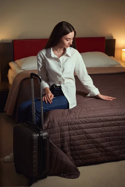 Woman Smoothing Bedspread While Sitting Large Bed Suitcase Next Her — Stock Photo, Image