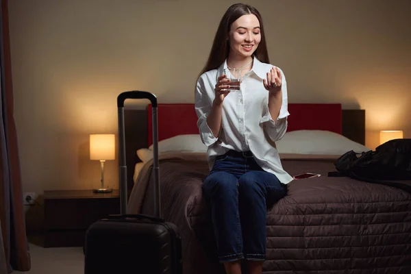 Gülümseyen Kadın Otel Odasında Büyük Bir Yatakta Otururken Elinde Bir — Stok fotoğraf