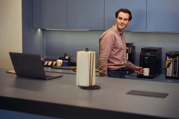 Zufriedener Firmenmitarbeiter Blickt Auf Computermonitor Während Becher Auf Kaffeemaschine Tropfschale — Stockfoto