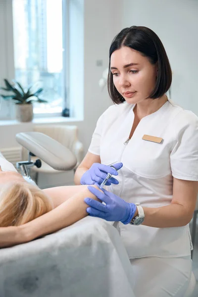 Glad Kosmetolog Gör Armbåge Injektion För Kvinna Liggande Soffan Kosmetolog — Stockfoto