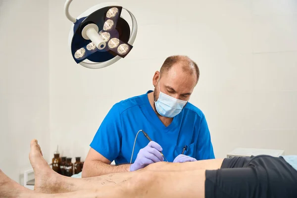 Photo Male Doctor Blue Coat Who Operates Patient Leg Electrocoagulator — Stock Photo, Image
