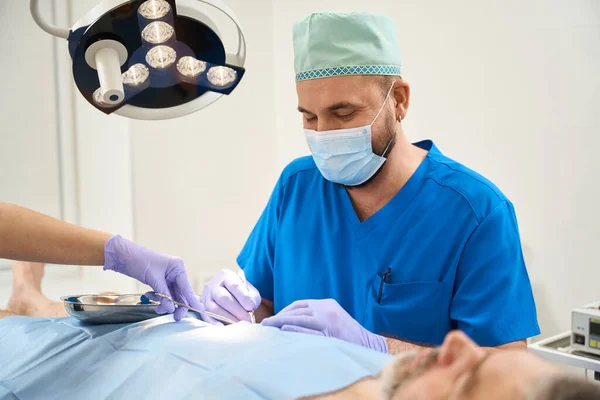 Chirurg Modrém Plášti Během Operace Těla Staršího Muže Ležícího Stole — Stock fotografie