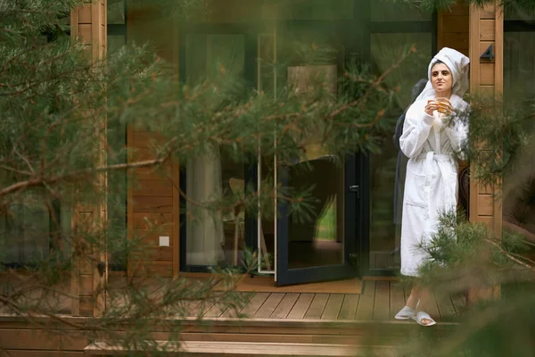年轻女子头戴毛巾 站在后院举杯 — 图库照片