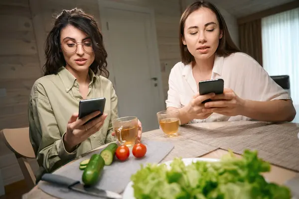 Vrouwelijke Vrienden Zitten Aan Tafel Eten Communiceren Internet Smartphone Keuken — Stockfoto