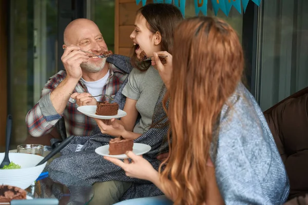 Lächelnder Vater Und Mutter Füttern Ihre Tochter Auf Der Veranda — Stockfoto