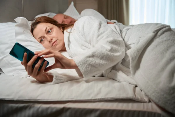 Fokuserad Mogen Kvinna Läser Nyheter Smartphone Skärm Närvaro Sin Man — Stockfoto
