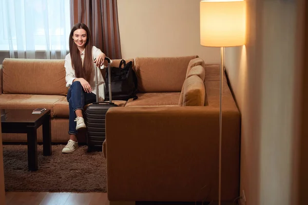 Kanepede Oturan Elini Bavula Koyan Gülümseyen Genç Kadın Bir Otel — Stok fotoğraf