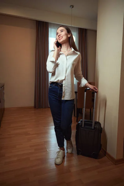 Happy Lady Talking Phone Holding Suitcase Handle Hotel Room — Stock Photo, Image