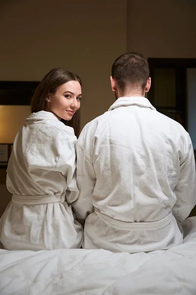 穿着浴衣的年轻女子和她的伴侣坐在宾馆房间里 很高兴 — 图库照片