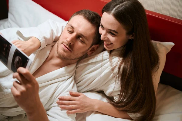 Happy Young Female Lying Bed Hotel Room While Demonstrating First — Stock Photo, Image