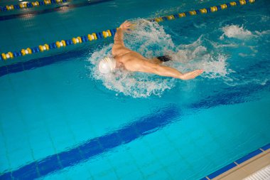 Beyaz şapkalı sporcu yüzme sporuyla meşgul, adam havuzda ısınmadan önce.