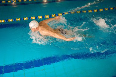 Beyaz şapkalı sporcu ve Google 'da yüzen sporcu, erkek havuzda antrenman yapmadan önce ısınıyor.