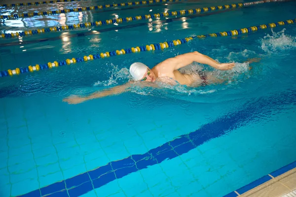 参加三项全能运动的男子 头戴白帽 戴着谷歌眼镜 在水里做运动 — 图库照片