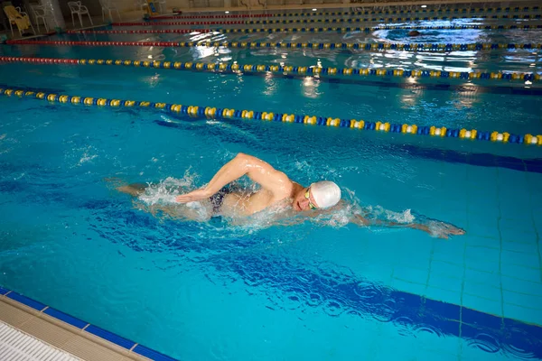 头戴白帽 戴着谷歌眼镜的男子在水里做运动 而男子则参加三项全能运动 — 图库照片