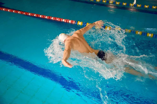 男性は蝶のスタイルで水の演習に従事している 選手はプールで訓練されています — ストック写真