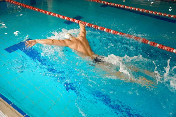 白い帽子をかぶった大人の男が水で練習に従事し 蝶のスタイルで泳ぐ — ストック写真