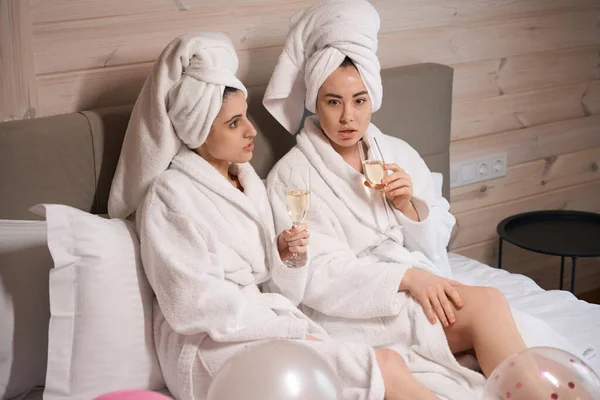 Två Kvinnor Badrockar Pratar Medan Ligger Stor Säng Hotellrummet Och — Stockfoto