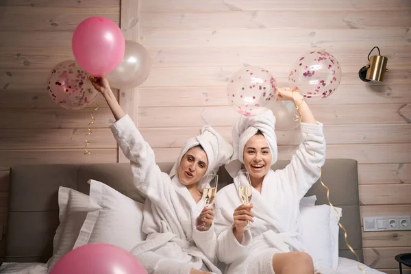 Zwei Lächelnde Frauen Mit Luftballons Und Champagnergläsern Sitzen Auf Einem — Stockfoto